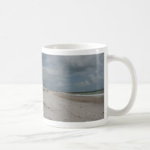 Plage et dune et jetée vides excepté une tasse à café