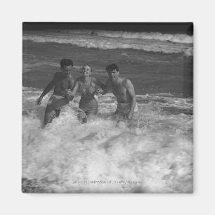 Aimant Deux jeunes hommes et femme jouant dans la vague