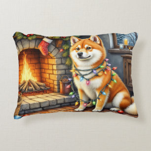 Akita sitzt neben dem Kamin mit Weihnachtslichtern Dekokissen