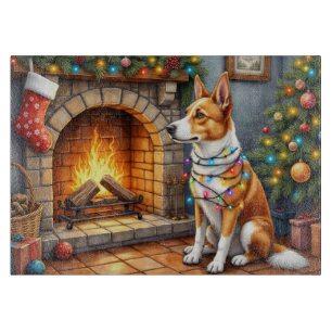 Australischer Kelpie vor dem Kamin mit Weihnachtsl Schneidebrett