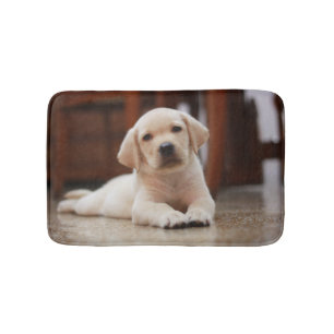 Baby-gelbes Labrador-Hündchen, das auf Bauch legt Badematte