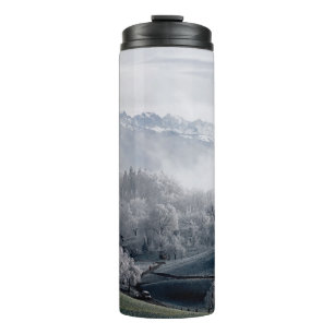 BÄUME NEBEN EINEM SCHNEEBEDECKTEN BERG WÄHREND DES THERMOSBECHER