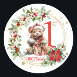 Bear Poinsettia Foliage Baby's First Christmas Runder Aufkleber<br><div class="desc">In diesem Design präsentiert sich ein Teddybär mit Weihnachtsmannmütze und ein Weihnachtskranz mit Poinsettia,  grünem Blattwerk und roten Beeren. Sie können Text nach Ihren Anforderungen anpassen.</div>
