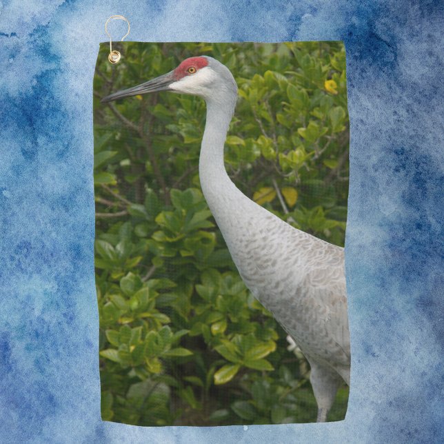 Bird Sandhill Crane Foto Golfhandtuch (A golf towel with a photograph of a sandhill crane bird in front of green leaves.)