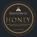 Black Honey Label mit Vintager Metallic-Goldbiene Runder Aufkleber<br><div class="desc">Der Name der Bibliothek sieht phantastisch aus in einem klassischen, weiß dekorativen Schriftart, der auf schwarzem Hintergrund kunstvoll in dunklem Gold reflektiert wird. Kontaktinformationen, Anschrift und Honignettogewicht werden im unteren Teil des Etiketts unter dem Wort "HONEY" geschrieben, das in einem goldgelben metallischen Schriftart im Mittelpunkt steht. Umrechnung des Nettogewichts von...</div>