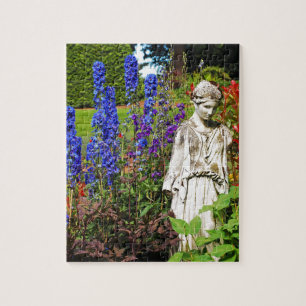 Blaue Delphinium-Blüte Garten und Göttin Statue