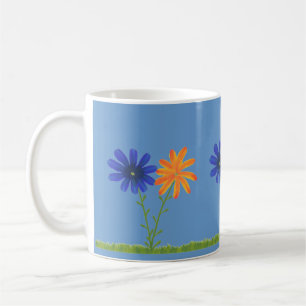 Blaue und orangefarbene Gänseblümchen mit Gras auf Kaffeetasse