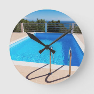 Blauer Swimmingpool mit Schritten in Meer Runde Wanduhr