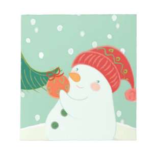 Bloc-note Un bonhomme de neige accrochant un ornement sur un