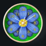 Blue Daisy Blume auf Green Beautiful Wanduhr<br><div class="desc">Diese hübsche Blumenuhr hat eine originelle, stilisierte Blume, in einem gedämpften Stil und farbenfroh blau. Die gelb-orangefarbenen Uhrennummern markieren die Zeit auf den zwölf Blättern. Der Hintergrund ist in einem abstrakten grün mit Motiven und ähnelt einem Gras. Dies ist eine helle, mutige Uhr für einen Gärtner oder jeden Liebhaber von...</div>