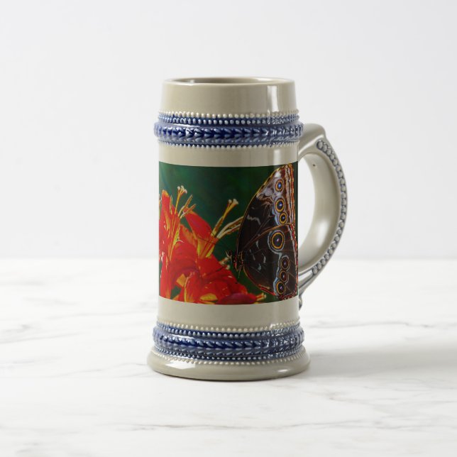 Blue morpho butterfly on Crocosmia Lucifer flowers Bierglas (VorderseiteRechts)