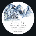 Blue Watercolor Mountain Rustic Boho Save the Date Runder Aufkleber<br><div class="desc">Blue Watercolor Mountain Rustic Boho Save the Date Square Sticker mit einer herrlichen Gebirgslandschaft mit hohen immergrünen Pinienbäumen, handgeschriebener Schrift und moderner Typografie für ein sauberes, minimalistisches Gefühl. Wenn der Ort Ihrer Hochzeit eine längere Stadt und Staat ist als das, was wir hier haben, haben die quadratischen Aufkleber mehr Platz...</div>