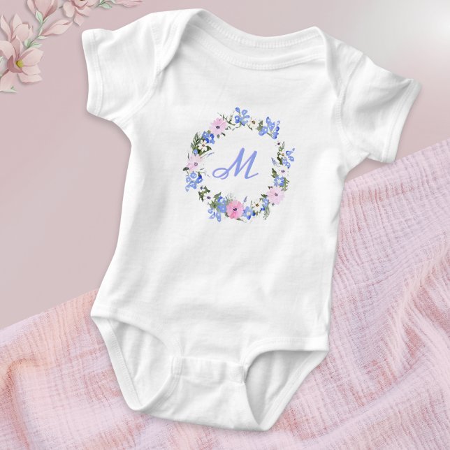 Body Jolie initiale florale en forme de cercle fleuri (A pretty baby bodysuit with pink, blue and white flowers in a circle around a monogrammed initial)