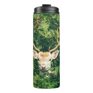BRAUNER UND WEISSER HIRSCH UMGEBEN VON GRÜNEN PFLA THERMOSBECHER