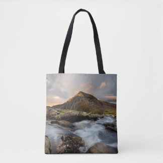BROWN MOUNTAIN NEAR BODY OF WATER UNDER CLOUDY SKY TASCHE