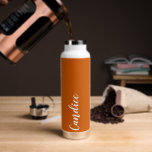 Burnt Orange Personalisiert Wedding Bridesmaid Trinkflasche<br><div class="desc">Geben Sie Ihrer Braut oder Trauzeugin diese trendige,  vakuumisolierte Wasserflasche,  die ihren Namen in weißem,  stilisiertem Schrift auf einem verbrannten orangen Hintergrund zeigt,  der zu Ihrem Hochzeitsfarbschema passt. Stellen Sie die Flasche nach Belieben durch Bearbeiten und Ersetzen des Namens durch Ihren eigenen Namen ein. Wählen Sie Ihre Wasserflasche.</div>