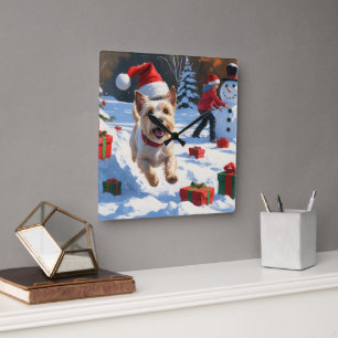 Cairn Terrier läuft im Schnee mit Weihnachtsmütze Quadratische Wanduhr