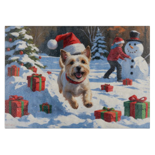 Cairn Terrier läuft im Schnee mit Weihnachtsmütze Schneidebrett