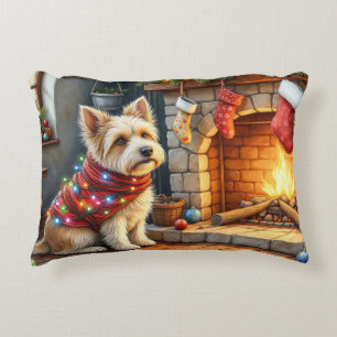 Cairn Terrier sitzt vor dem Kamin mit Weihnachtsli Dekokissen
