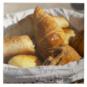 Carreau Un panier petit-déjeuner en osier avec croissants.