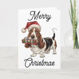 Carte Basset Hound à Santa chapeau présent dans la bouch
