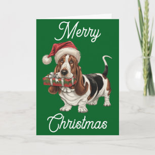 Carte Basset Hound avec un chapeau de Père Noël tenant u