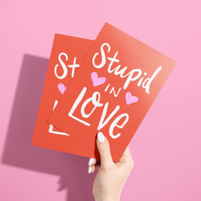 Carte « Fou amoureux de toi juste parce que » (Bold red card with pink hearts and white lettering "stupid in love ... with you" and custom text)