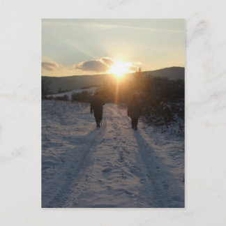 Carte Postale Couple se promenant dans la neige au coucher du so