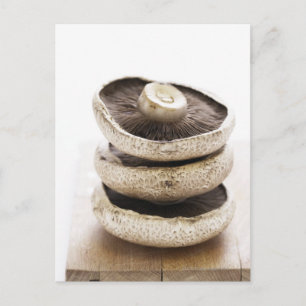 Carte Postale Trois champignons plats en pile sur une planche en