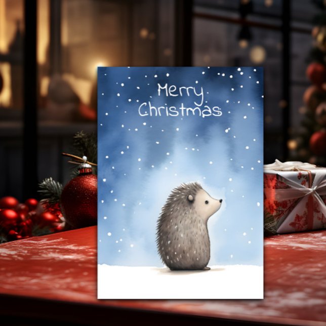 Cartes Pour Fêtes Annuelles Noël de Hérisson (A Christmas card with a cute illustration of a hedgehog is shown on a table with decorations around )