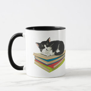 Chat dormant sur des livres de tasse
