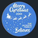 Christmas Santa’s sleigh reindeers holiday Runder Aufkleber<br><div class="desc">Zeigen Sie, wie sehr Sie an den Zauber von Weihnachten und Weihnachtsmann glauben, mit diesem Weihnachtsfamilienrundaufkleber, der die Silhouette des Schlittens des Weihnachtsmanns in Weiß mit seinen Rentieren zeigt und auf Sternenwegen fliegt. Die Titelschrift auf oben liest Frohe Weihnachten in weißer handgeschriebener Schrift. Der Text ist leicht an Ihre Wünsche,...</div>