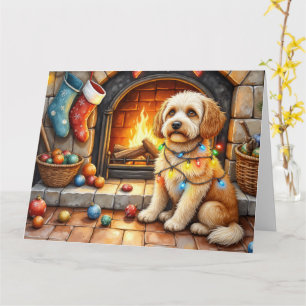 Cockapoo sitzt neben dem Kamin mit Weihnachtslicht Karte