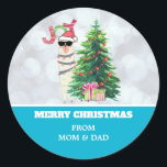 Cooler Llama auf Silver Bokeh & Icy Blue Christmas Runder Aufkleber<br><div class="desc">Weihnachtsaufkleber personalisiert mit Ihrem Namen. Erstellt mit einer lustigen Illustration. Ein niedliches Lamm mit schwarzer Sonnenbrille und einer roten Weihnachtsmannmütze. Stehend hinter einem Weihnachtsbaum mit festlichen Geschenken. Das Wort Joy schrieb über seinem Kopf in einem bunten Schriftart. Silver Bukh Hintergrund mit einem eisblauen Rand. Whimsical und Spaß Weihnachten Thema Design....</div>