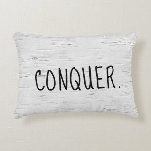 Coussin décoratif avec texte CONQUER sur un boulea