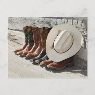 Cowboy-Hut in Reihe von Cowboy-Stiefeln außerhalb  Postkarte