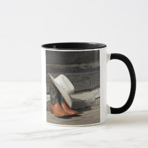 Cowboyhut auf Cowboystiefeln außerhalb eines Tasse