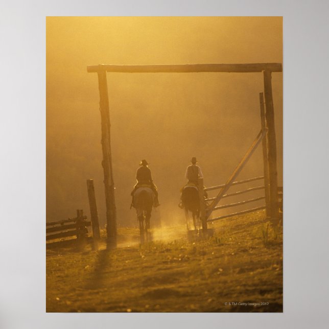 Cowboys fahren bei Dämmerung durch Tor Poster (Vorne)