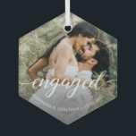 Custom Foto First Christmas Verlobt White Script Ornament Aus Glas<br><div class="desc">Mit unserem "Unser erstes Weihnachtsfest Verlobt" Custom Foto Names Keramik Ornament, ein wahrhaft besonderer Sake für das frisch verlobte Paar. Dieses personalisierte Ornament erlaubt es Ihnen, diesem fröhlichen Meilenstein zu gedenken und Ihrem Weihnachtsbaum eine persönliche Touch hinzuzufügen. Das Ornament enthält ein elegantes Drehbuch, das "verlobt" liest und dieses spannende Kapitel...</div>