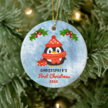 Cute Cartoon Penguin Baby's First Christmas Foto Keramik Ornament<br><div class="desc">Niedlicher Cartoon Pinguin in Hut und Schal mit zwei heiligen und beeren Keuchen und einem rot-weißen Geschenk zu seinen Füßen "First Christmas" Name und Jahresdesign mit BackFoto.</div>