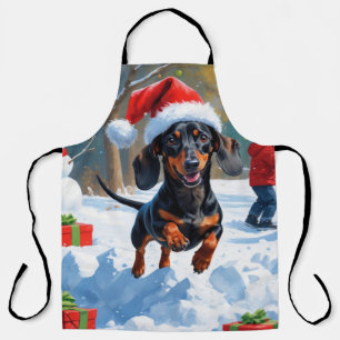 Dackel läuft im Schnee mit Weihnachtsmütze Schürze