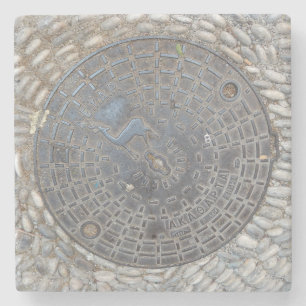 Deckel eines Kanalschachts und Kopfsteinpflaster-S Steinuntersetzer