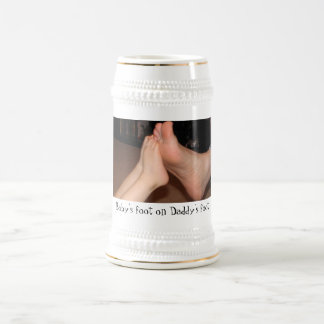 Der Fuß des Babys auf dem Fuß des Vatis Bierglas