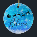 Der Weihnachtsmann und sein fliegender Rentier - G Keramik Ornament<br><div class="desc">Weihnachtsschmuck mit einer schwarzen Silhouette des Santa-Reitens in seinem Schlitten,  der von seinen Rentieren über den Himmel gezogen wird. Glauben Sie,  in einem trendigen roten Skript-Schriftart geschrieben. Der Hintergrund ist ein eisblau frostiges Schneeflockendesign.</div>