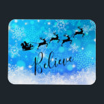 Der Weihnachtsmann und sein fliegender Rentier - G Magnet<br><div class="desc">Weihnachtsmagnet - flexibler Stil,  mit einer schwarzen Silhouette des Santa-Reitens in seinem Schlitten,  der von seinen Rentieren über den Himmel gezogen wird. Glauben Sie,  in einem trendigen Skript-Schriftart geschrieben. Der Hintergrund ist ein eisblau frostiges Schneeflockendesign.</div>