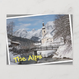 Die Kirche im Schnee mit den Alpen im Winter Postkarte