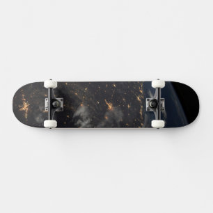 Die Stadt beleuchtet nachts auf der Erde Skateboard