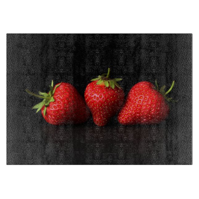 Drei Erdbeeren auf schwarzem Cbcnm Schneidebrett (Vorderseite)