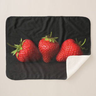 Drei Erdbeeren auf schwarzem Sbcna Sherpadecke