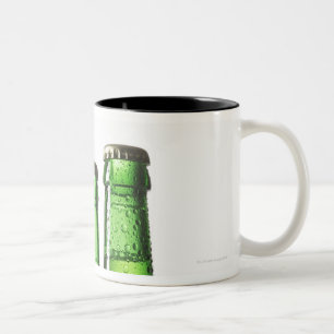 Drei grüne Flaschen Bier auf weißem Hintergrund, Zweifarbige Tasse